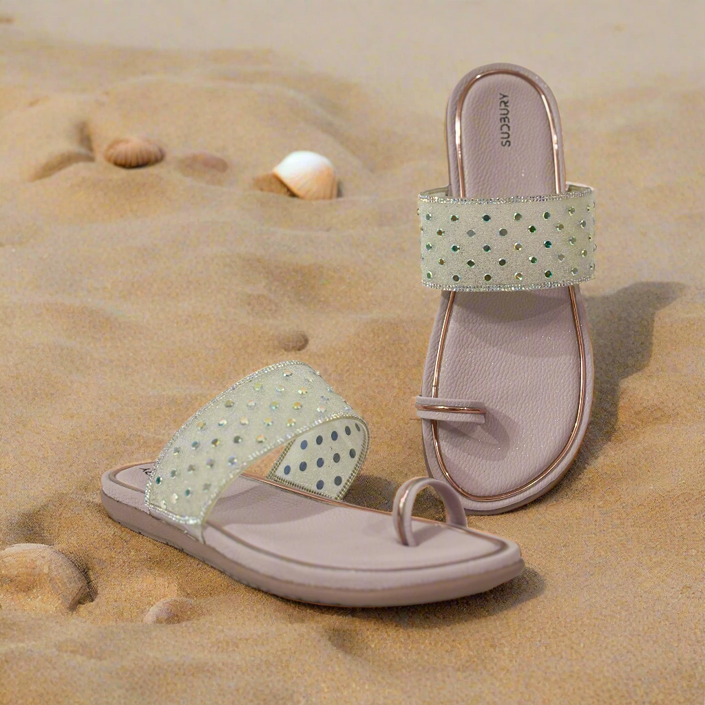 Pair of sandals with glittery straps on a pink background