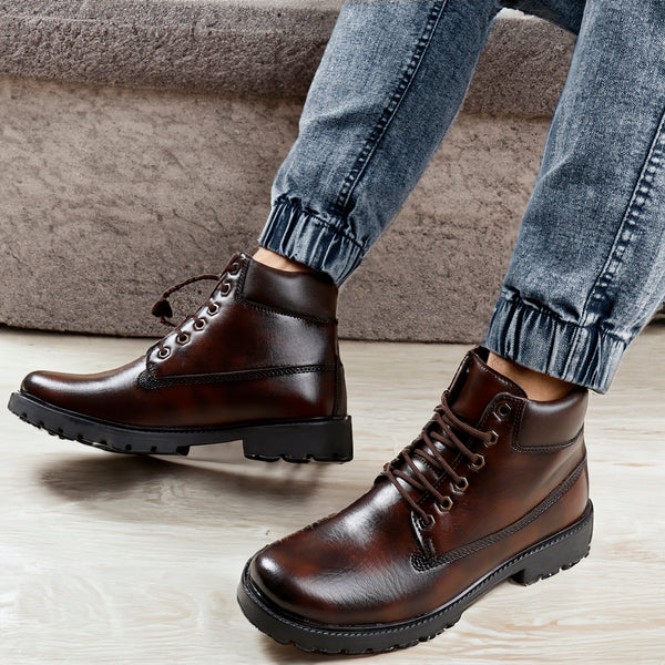A pair of brown men's ankle lace-up boots with a visible sole, worn by a model paired with blue jeans.